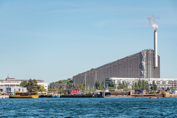 Amager Bakke, Slope or Copenhill, incineration plant, heat and power waste-to-energy plant and recreational facility in the district of Amager, Copenhagen, Denmark, with modern buildings and boats - obrazy, fototapety, plakaty