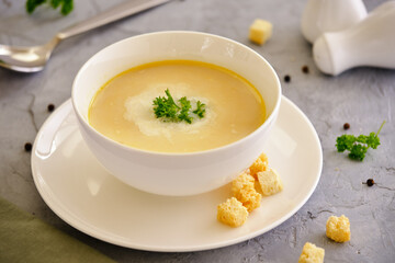 Vegetable cream soup with chicken breast and herb in a white bowl on a gray background