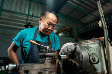 Fototapeta na wymiar Portrait of Asian senior man working as a steel lathe is preparing work and equipment to turn steel and a small lathe in the family industry.