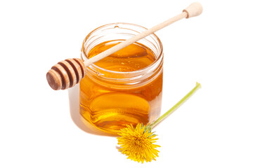 Honey dripping from honey dipper in glass jar with dandelion. Healthy food concept