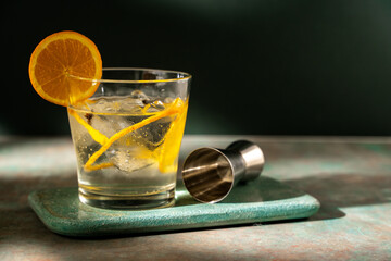 Glass of gin tonic with orange slice and ice. dark green background - obrazy, fototapety, plakaty