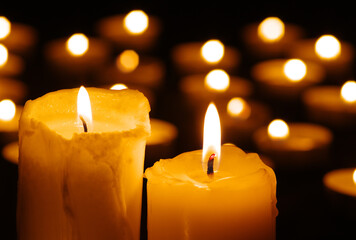 Two burning candles in the dark