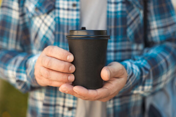 Ma holding in hands takeaway black paper cup of coffee