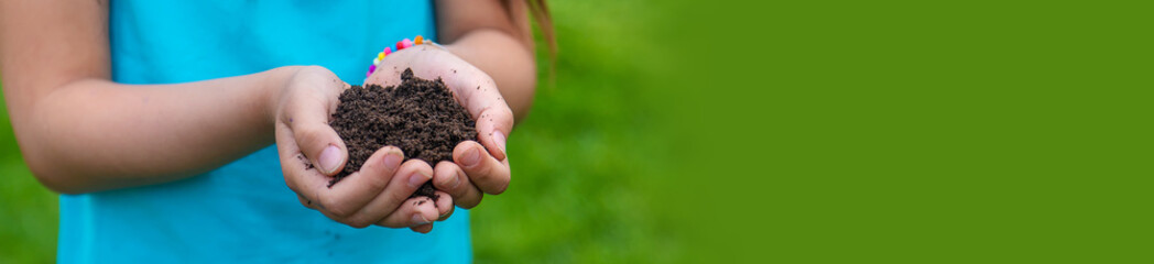 The child holds the soil in his hands. Selective focus.