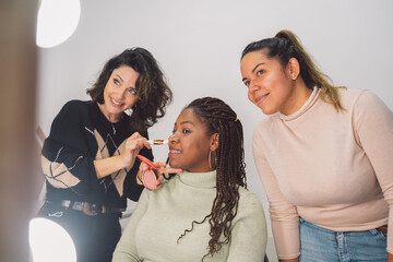 Diverse women looking at mirror during makeup application