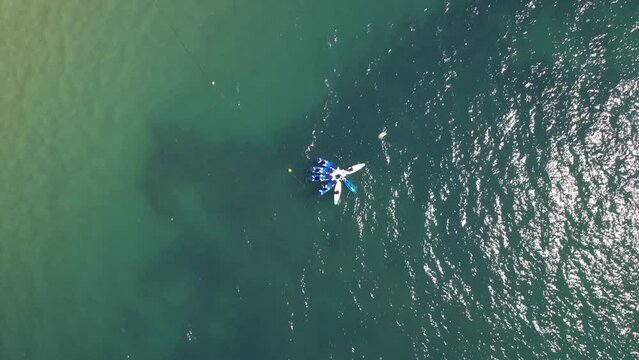 Aerial view of Stand Up Paddle Surfing on crystal water ocean view with reveal of Conceicao Beach and Cascais cityscape, Portugal on a sunny day
