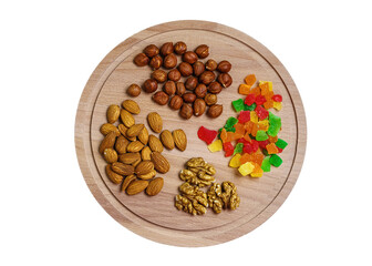 Various nuts and candied fruits on a round wooden cutting board.