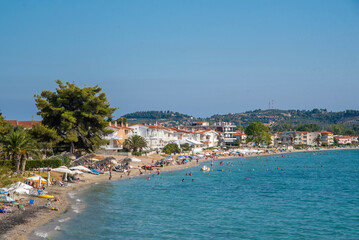 Fototapeta na wymiar Beautiful view of iconic Posidi sandy beach, paradise cape and Peninsula in Kassandra, Halkidiki, North Greece. People walking, swimming and sunbathing on sea beach.