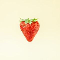 Minimal composition with fresh red strawberry against bright sandy background.