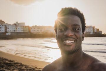 Young african man taking a selfie with sunset in the background on the beach after surf session