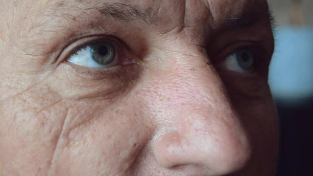 Face and eyes of mature person. Close up of large wrinkles on the face of senior male. Portrait of attractive elderly man.