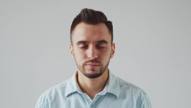 Young Caucasian Brunet Man is Looking at the Camera on a Light Gray Background. Studio Male Face Portrait. Natural Day Light.