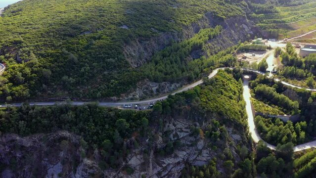 Aerial view of a curvy mountain road in sunny Setubal, Portugal - pan, drone shot