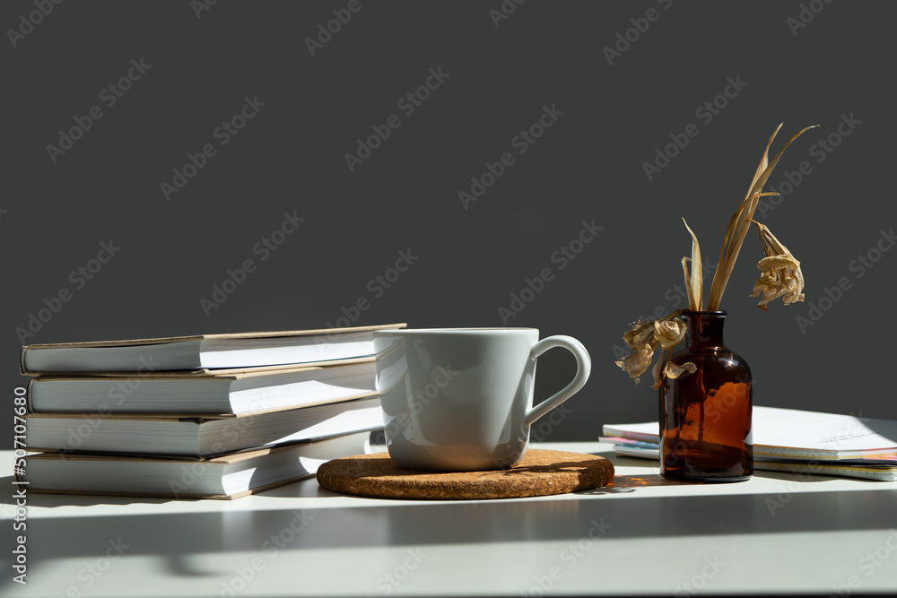 Wall mural books, a mug of tea and a vase of flowers.