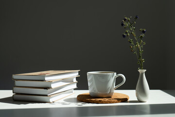 books, a mug of tea and a vase of flowers.