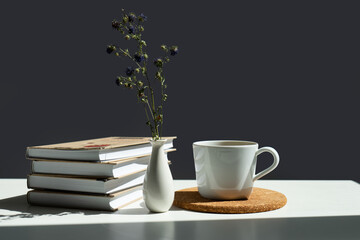 books, a mug of tea and a vase of flowers.