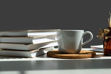 a stack of books with a mug of tea on a white table.