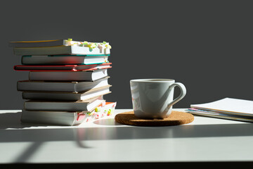 a stack of books on a table with a mug of cha.