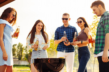 Friends have a barbecue party outdoors during outdoor recreation. Group of friends drink drinks and eat grilled