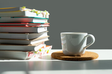 a stack of books with a mug of tea on a white table.