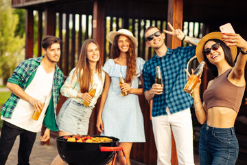 group of cheerful young friends having a barbecue party in the backyard, taking a selfie on a mobile phone