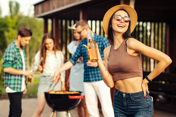 happy beautiful young woman in a hat with lemonade in the foreground, with a group of friends...