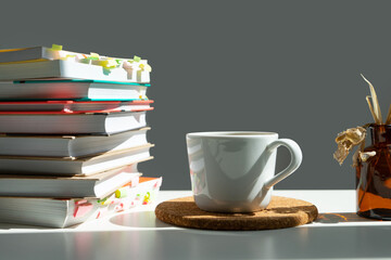 a stack of books with a mug of tea on a white table.