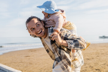 Young father having fun with daughter in panama hat on beach in Treviso.