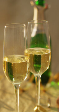 Vertical image of two glasses of champagne and open champagne bottle on table