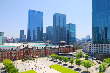 新緑と青空の東京駅、丸の内南口の駅舎と高層ビル群（東京都千代田区）
