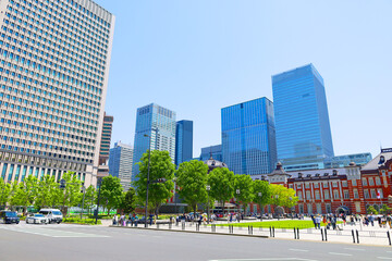 新緑と青空の東京駅、丸の内南口の駅舎と高層ビル群（東京都千代田区）