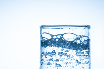 Ice cube fell into the glass of water. Water splashed from the clear glass. Fresh concept