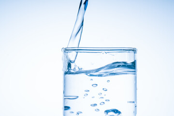 Ice cube fell into the glass of water. Water splashed from the clear glass. Fresh concept