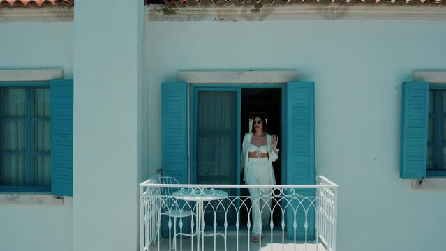 Young woman opening a window on a beautiful blue and white balcony in a house on Paros Island Greece