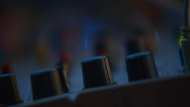 In a very close fixed plane, the camera focus travels through various synthesizers, going from the sequencer buttons to another synthesizer further away and returns to the sequencer when the beat pass