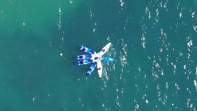 Aerial view of Stand Up Paddle Surfing on crystal water ocean view with reveal of Conceicao Beach and Cascais cityscape, Portugal on a sunny day