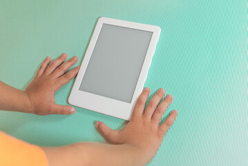 Ebook reader over green background - being held by the hand of a child