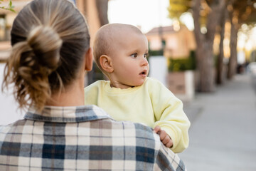 Naklejka premium Blurred man holding toddler kid on urban street.