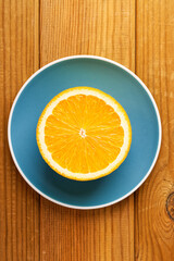 Half of the orange fruit in a saucer on a wooden table. Top view.