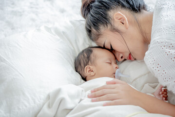 Obraz na płótnie Canvas baby and asian mother sleeps and touches her child with tenderness and cherishness
