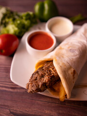 seekh kabab shawarma wrap with fries, tomato sauce and drink top view of arabic street food on wooden background