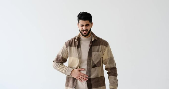 Man suffering from severe stomach ache over white background