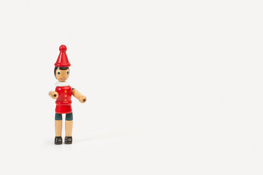 Juguete de personaje de madera de ni&ntilde;o de nariz larga de Pinocho sobre un fondo blanco liso y aislado. Vista de frente. Copy space