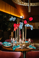 Wedding decorations. Festive table decorated with compositions of colored flowers. On the tables are plates, glasses, candles and cutlery
