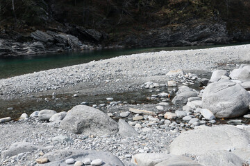 The clear Maggia River flowing along the Stones in the Maggia Valley in the Ticino in Switzerland