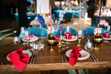 Wedding decorations. Festive table decorated with compositions of colored flowers. On the tables are plates, glasses, candles and cutlery