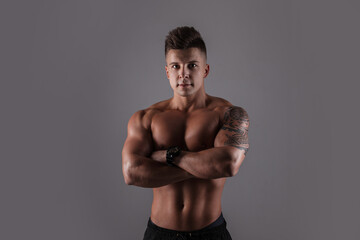 Fashionable handsome athletic bodybuilder guy with hair with a muscular naked body in a studio on a...