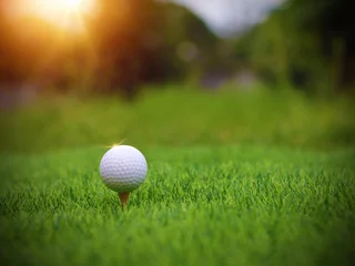 Poster Golf ball close up on tee grass on blurred beautiful landscape of golf background. Concept international sport that rely on precision skills for health relaxation. © Sittipol 