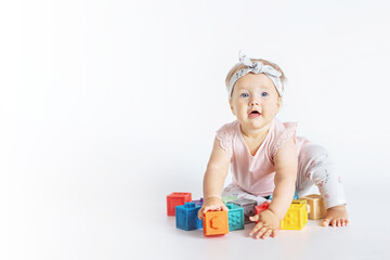 little caucasian baby girl ten months old playing with educational silicon toys at home or nursery. Child having fun with colorful toys on white background