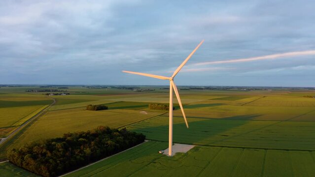 Alternative energy sources with wind mill green energy production. Aerial drone video. windmill park with stormy clouds and a blue sky. Wind turbines on the green lush field. Dark stormy clouds. 